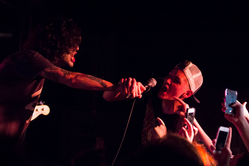 (Left) Dan Lambton, lead singer of the band Real Friends, holds his microphone out to an audience member who was crowdsurfing during their set. 