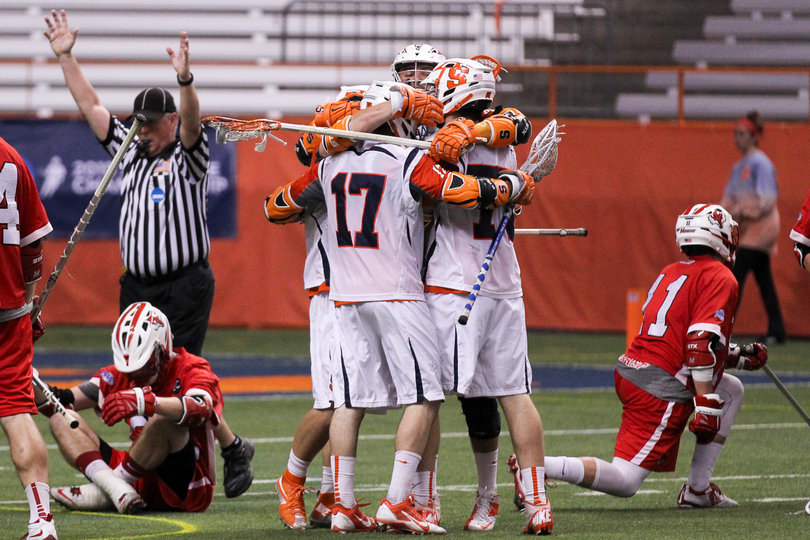 The Syracuse offense celebrates following a goal. The Marist defenders sit angry on the turf. 