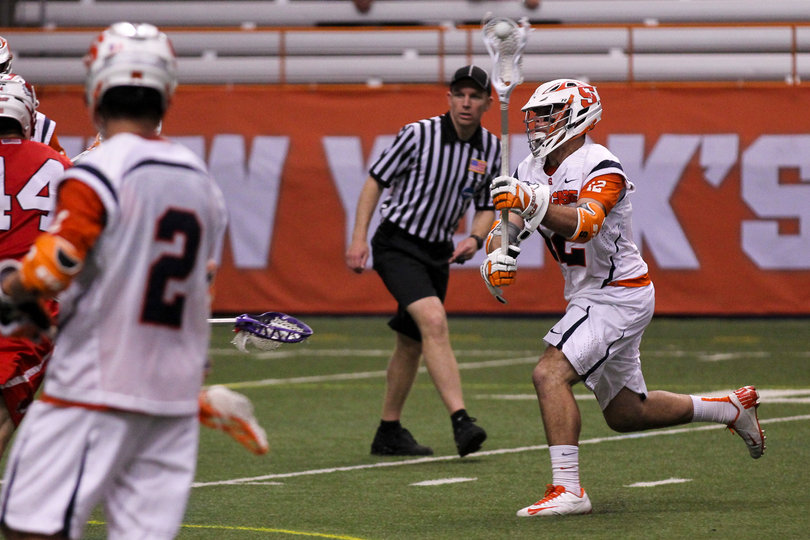 A Syracuse player looks to make a move on offense while Kevin Rice looks on. 