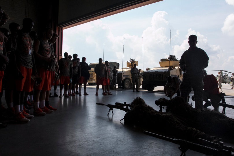 Syracuse players look on through a camouflage simulation. The two service members lay completely still through the showing. 