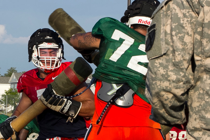(From left) Junior defensive end Luke Arciniega shuts his eyes while absorbing a swing by senior offensive tackle Ivan Foy.