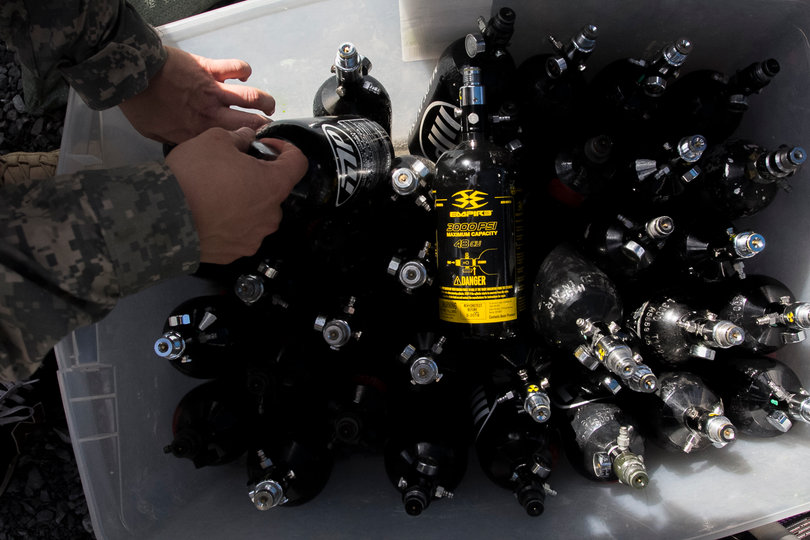 A soldier reaches in to a box full of canisters. 
