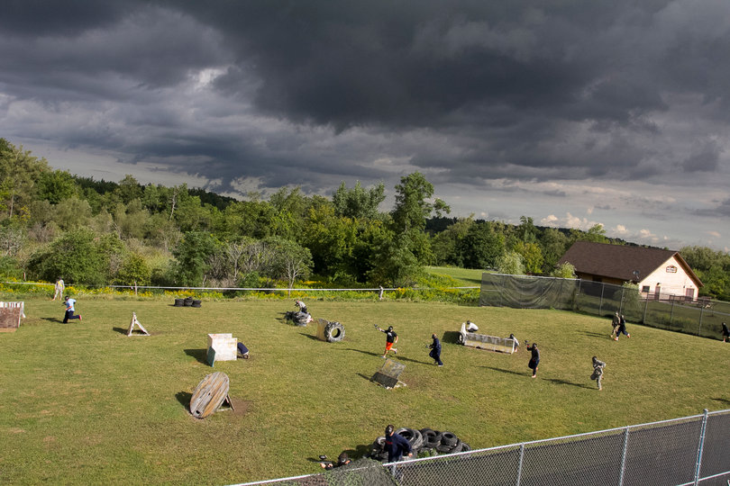 Members of SU push forward as storm clouds roll in above the paintball field.