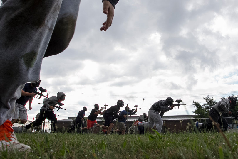 Members of the Orange take aim with their paintball guns while creeping toward their opponents.