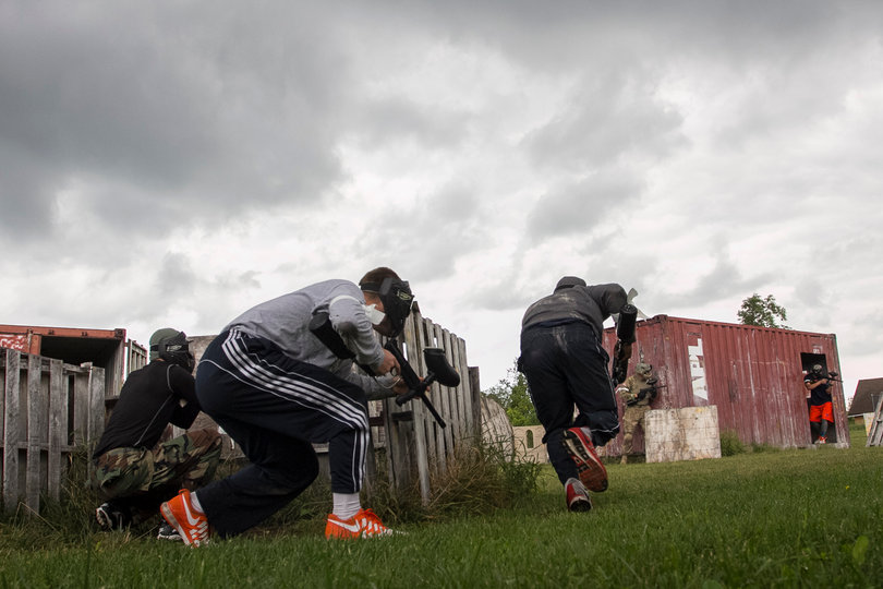 Players crouch behind barriers as others plan their attack.