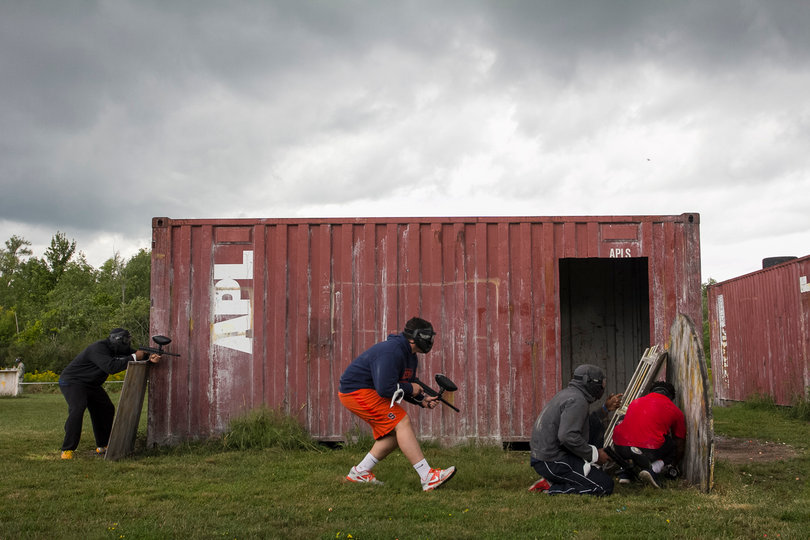 Teammates cram behind multiple wooden shields while keeping an eye on the opposition.