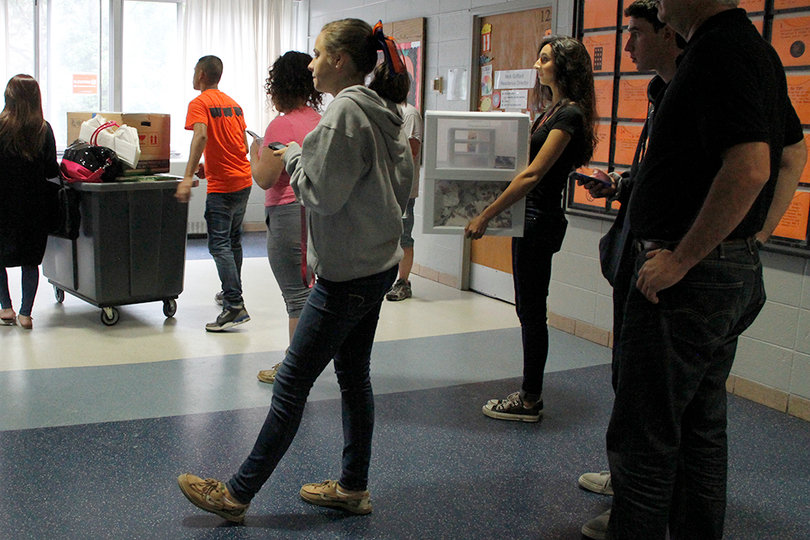Individuals wait in line for the elevator to bring their belongings up to their room.