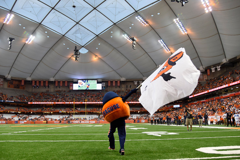 Otto the Orange storms the Carrier Dome field waving a flag branding his likeness on it.