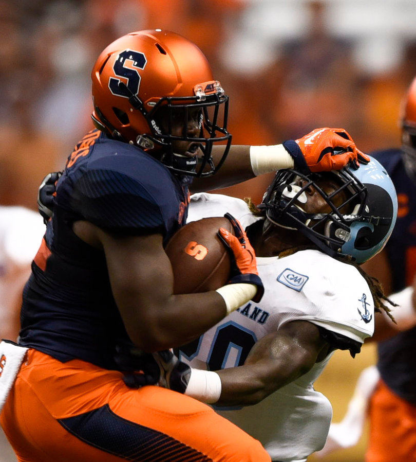 A Syracuse player with the ball stiff arms a Rhode Island defender.