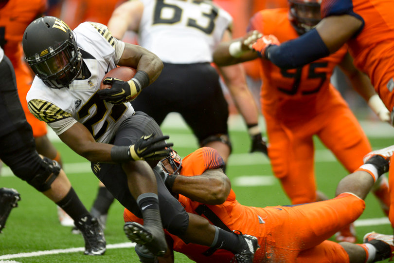 A Syracuse defender makes a tackle on a Demon Deacons' back running with the ball.