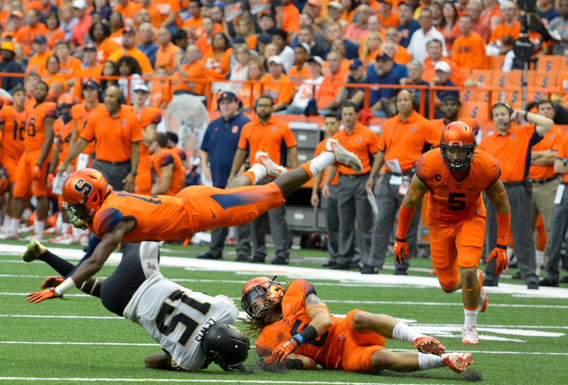 A Syracuse defender flies over Demon Deacons receiver Cortez Lewis trying to make a tackle.