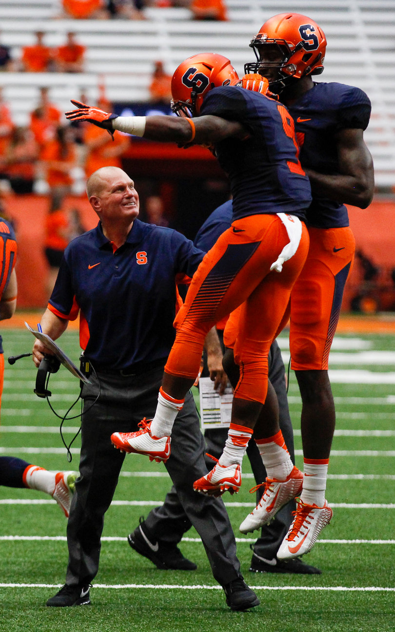 Syracuse head coach Scott Shafer celebrates with Brisly Estime (9) and another SU player.