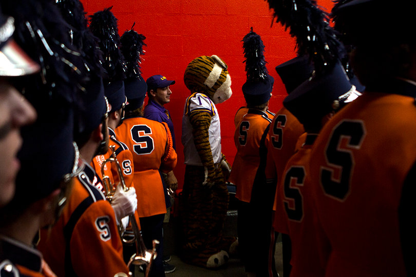 The SU marching band walks onto the field alongside LSU's mascot. 