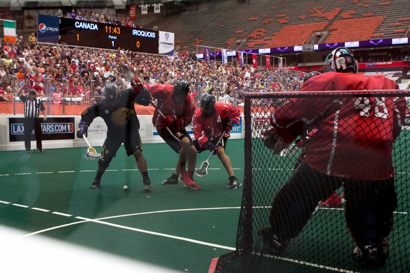 A Canadian and Iroquois player try to box each other out for a loose ball near Canada's crease. 