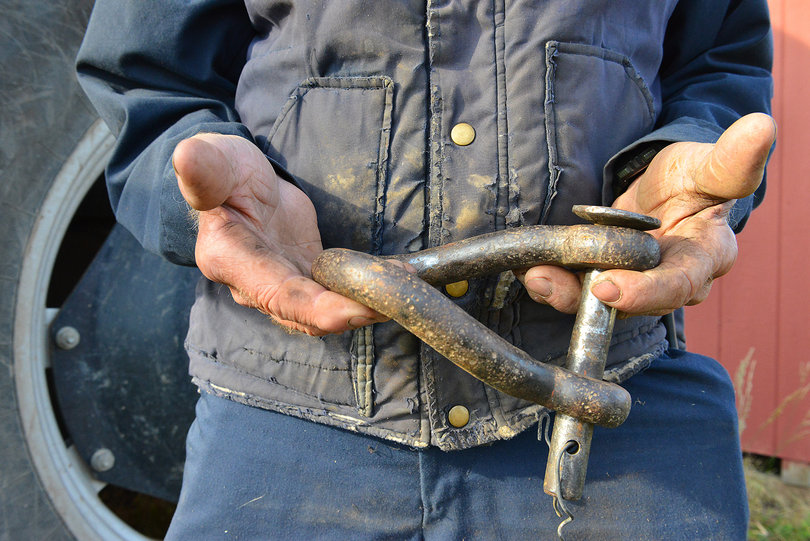 Abbott's cracked hands hold a bolt that connects the tractor to different trailers. 