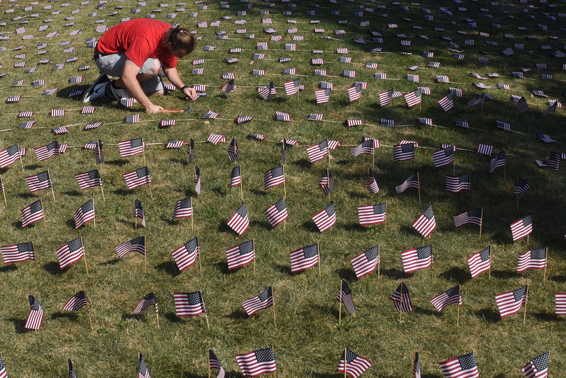 Aviram Krell,a  junior in the College of Arts and Sciences, places U.S. flags on an infield at SU in remembrance of 9/11. Nearly 3,000 people died during the attack 14 years ago and each year, colleges around the country honor the victims with acts such as this.