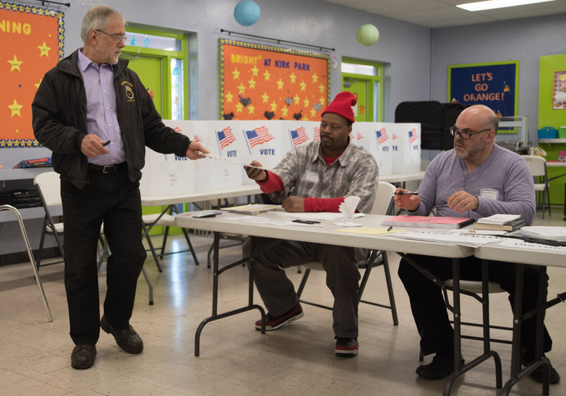 Howie Hawkins, Green Party city auditor candidate, returns the voting materials to James Newton and Jayme Martin after voting at the Kirk Park Community Center. The polls opened at 6 a.m. and closed at 9 p.m. 