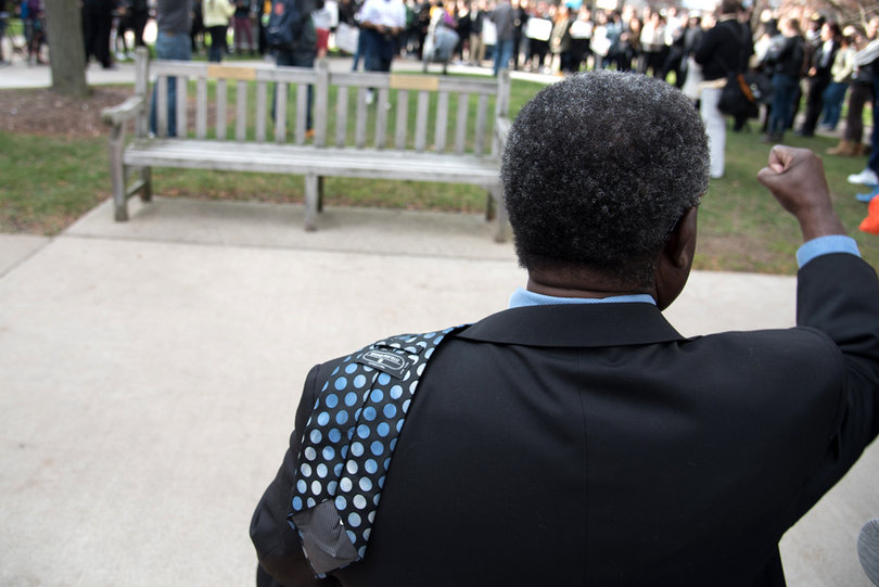 James Duah-Agyeman, directory of the Office of Multicultural Affairs, cheers as he watches protesters gather on the Quad to stand in solidarity with Mizzou. Duah-Agyeman said he is often nearby during such gatherings to ensure the students’ rights are observed and that the students don’t do anything that could get them in trouble.