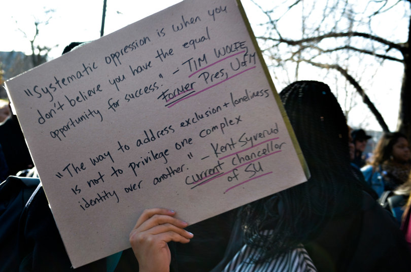 A student holds a sign with a quote from Tim Wolfe, former president of Mizzou, that reads: "Systematic oppression is when you don't believe you have the equal opportunity for success." A quote from Chancellor Kent Syverud was also written on the sign: "The way to address exclusion and loneliness is not to privilege one complex identity over another."