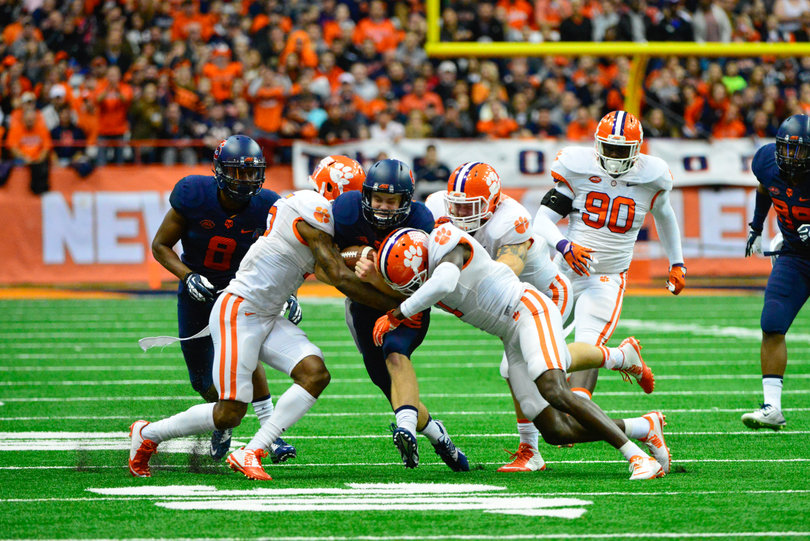 An Orange ball-carrier is sandwiched between two Clemson players.