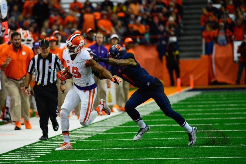 A Clemson receiver runs with the ball along the sideline.