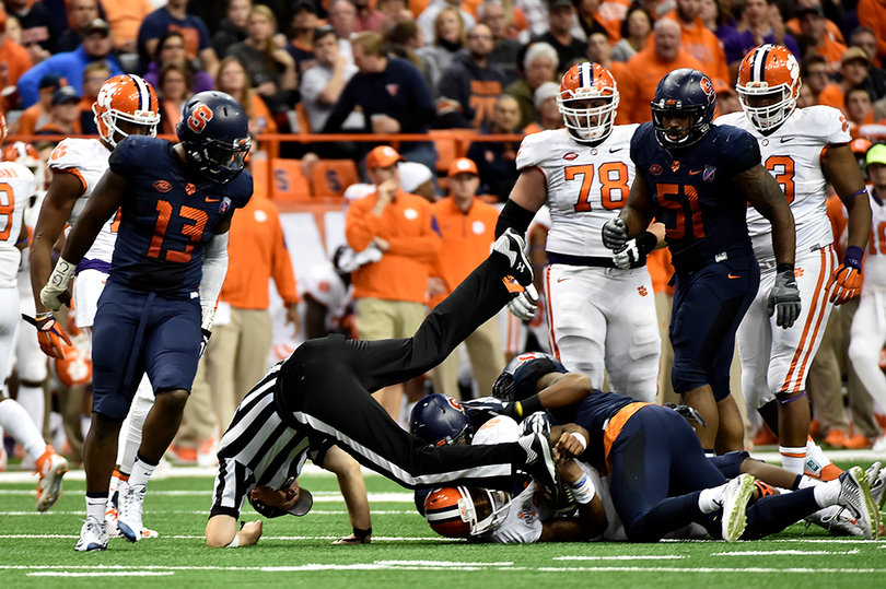 A referee is taken out as a Syracuse defender dragged the Clemson ball-carrier into him.