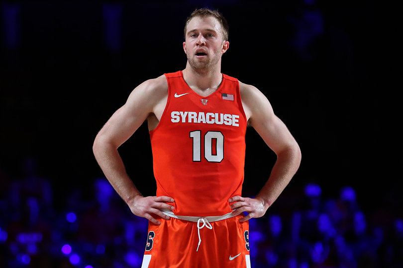 Cooney stands with his hands on his hips while another player shoots a free throw.