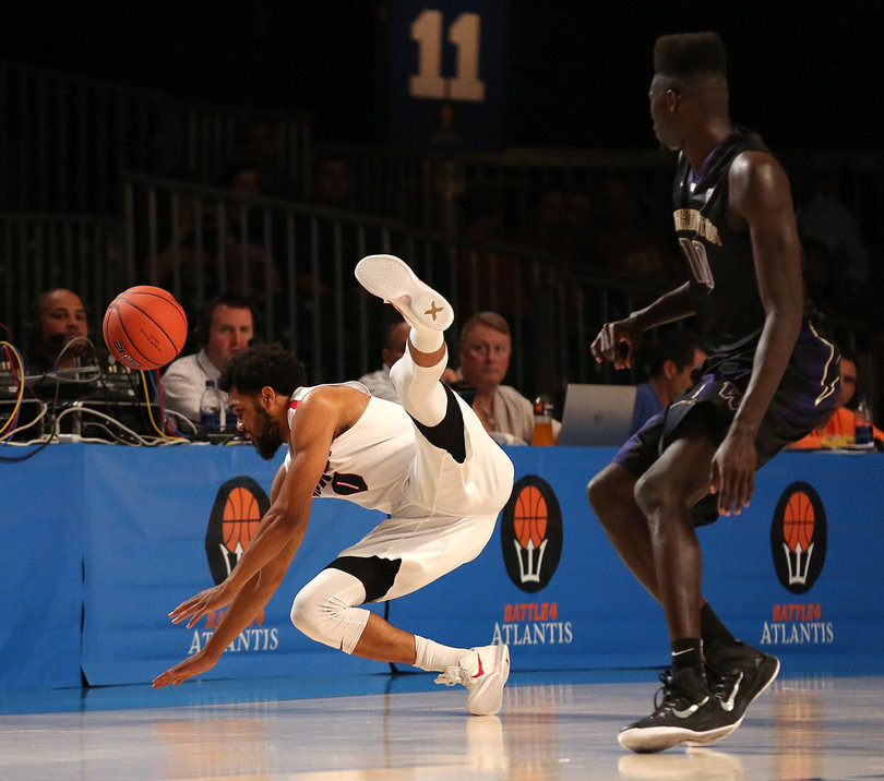 Melson dives on the court for a loose ball as Washington's Malik Dime stands and watches.