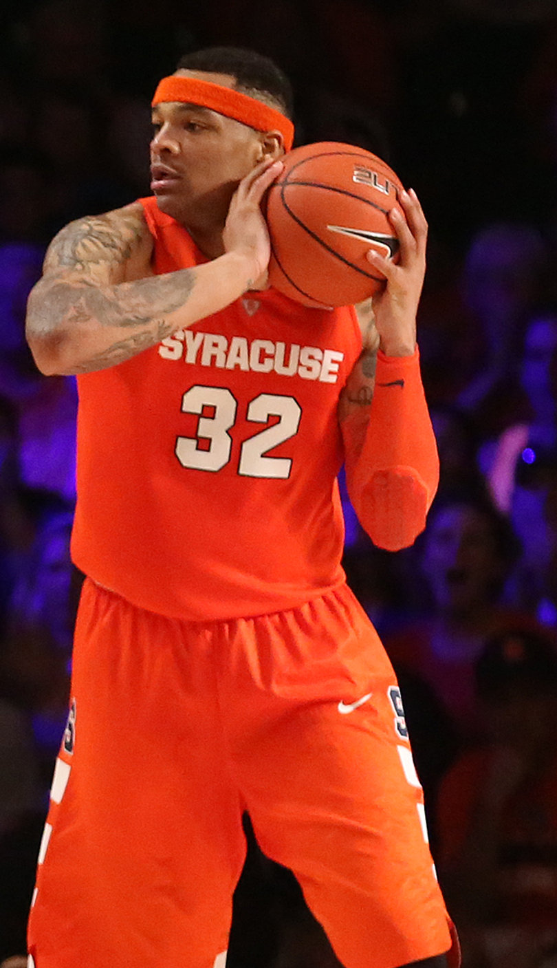 Coleman holds the ball near his face while surveying the rest of the court.