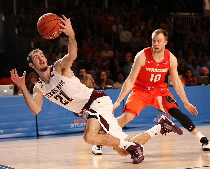 Texas A&M's Alex Caruso falls to the ground as Cooney stands nearby.