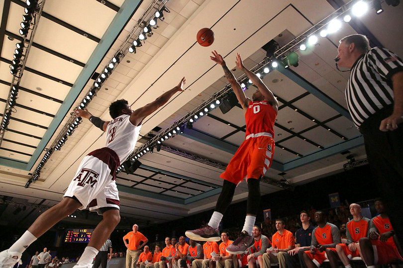 Gbinije shoots a 3 from the corner with Gilder reaching his arm forward to try and defend it.