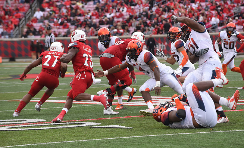 SU defensive lineman Donnie Simmons tips over and linebacker Zaire Franklin reaches his hand out in pursuit of Cardinals running back Brandon Radcliff. 