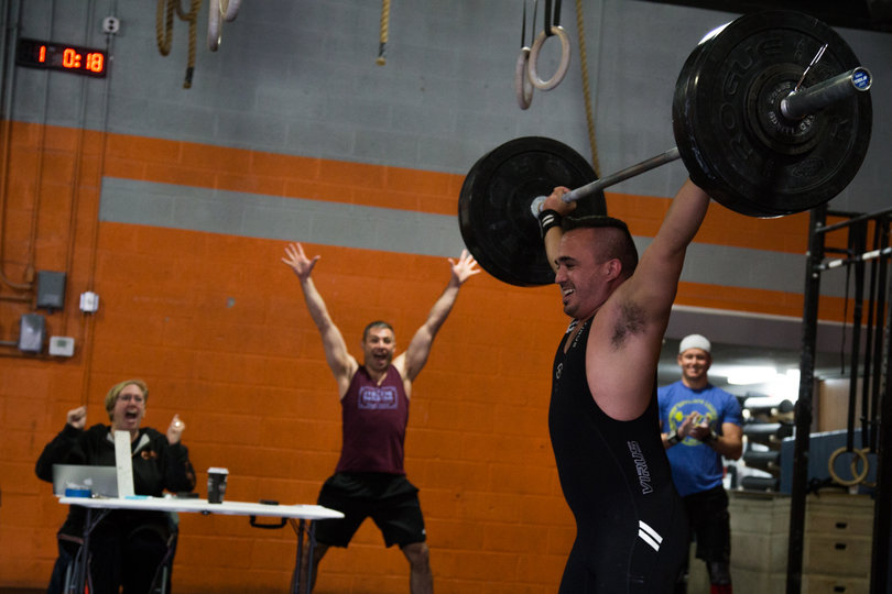 Chad Martin completes a Power Snatch as the crowd, including Jeff Treistman, cheers him on.