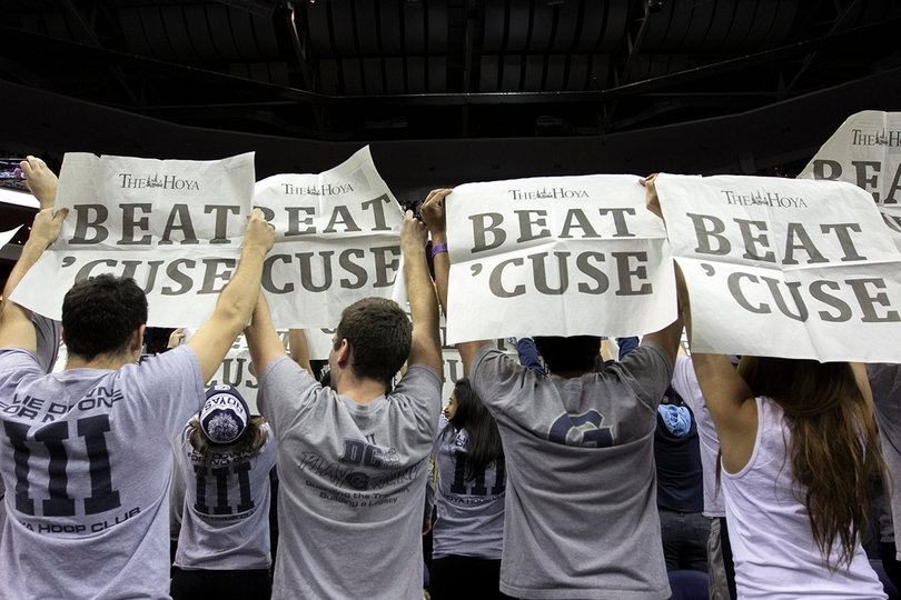 Georgetown students hold up newspapers that say "Beat 'Cuse" on them. 