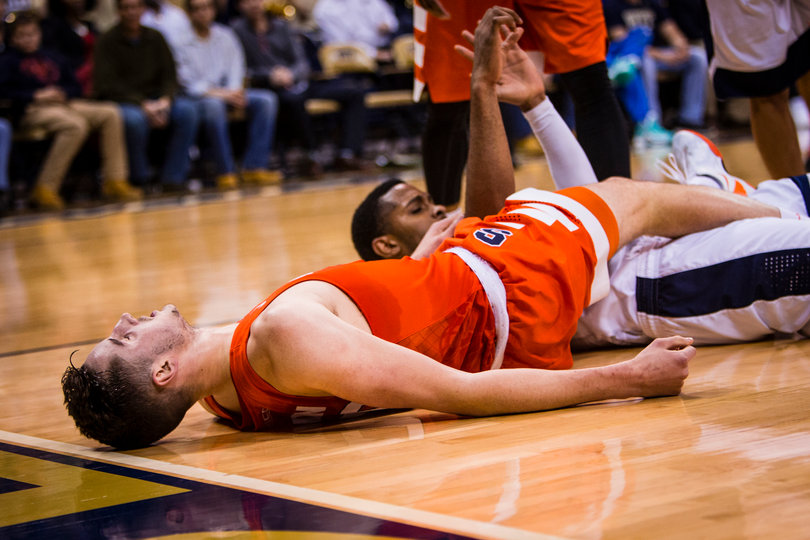 Lydon lies horizontally on the court with his right leg on top of a Pittsburgh player.