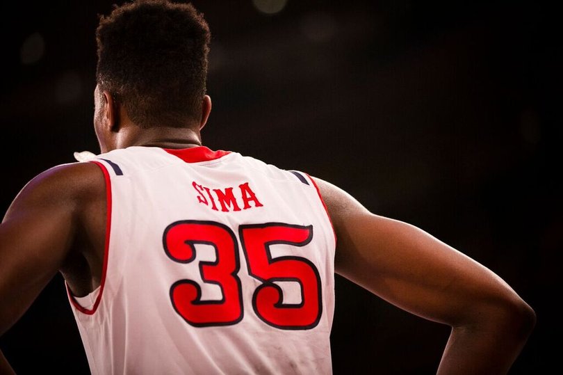 Yankuba Sima looks on while his hands are on his hips.