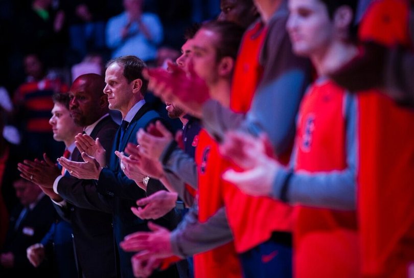 Members of Syracuse, including interim head coach Mike Hopkins, clap before the game starts. 
