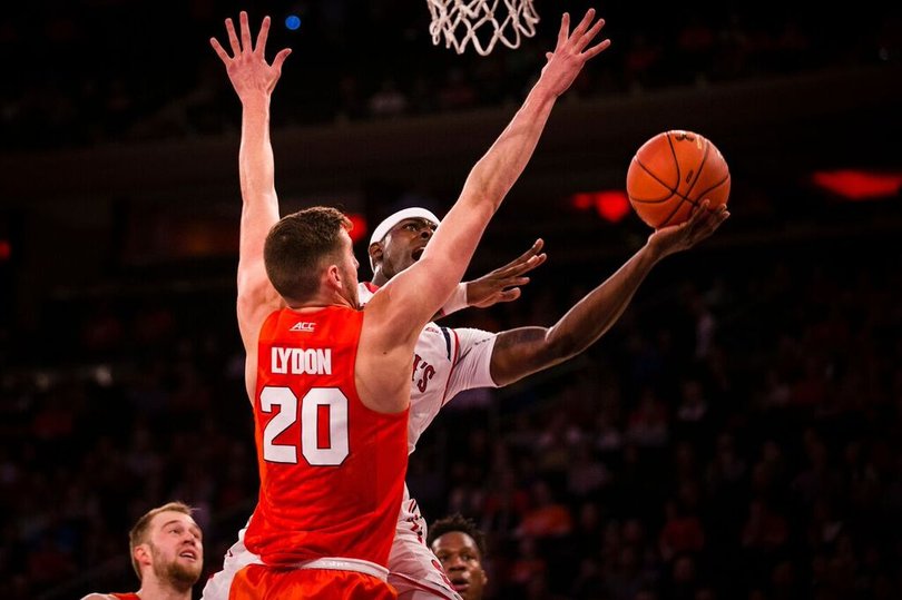 Lydon extends his arms straight up while defending near the basket.