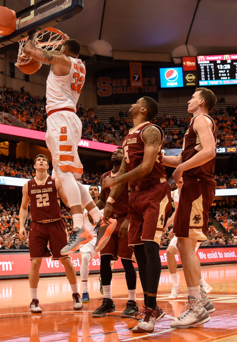 Syracuse center Dajuan Coleman hangs onto the rim after flushing a dunk. Coleman had 11 points and five rebounds.
