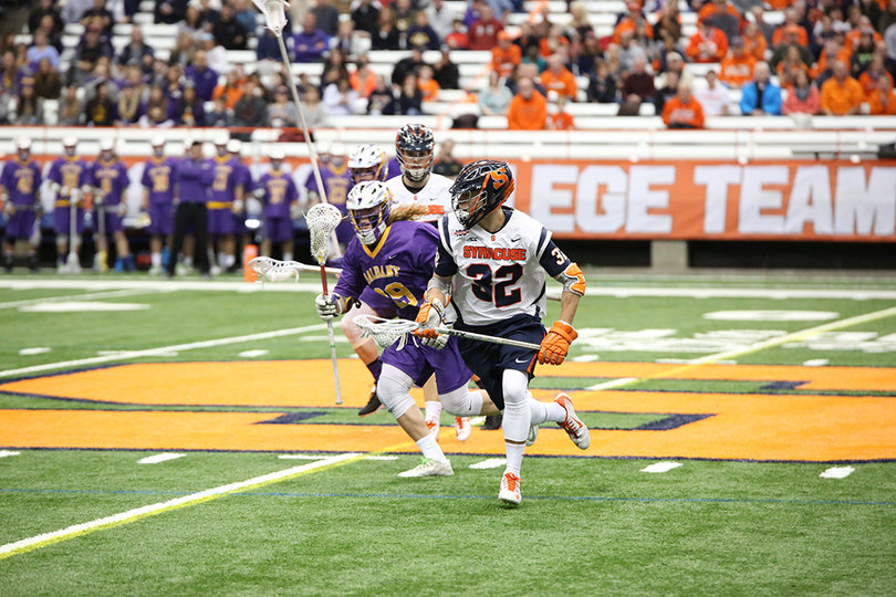 Grimm runs near the middle of the field as an Albany player chases after him.