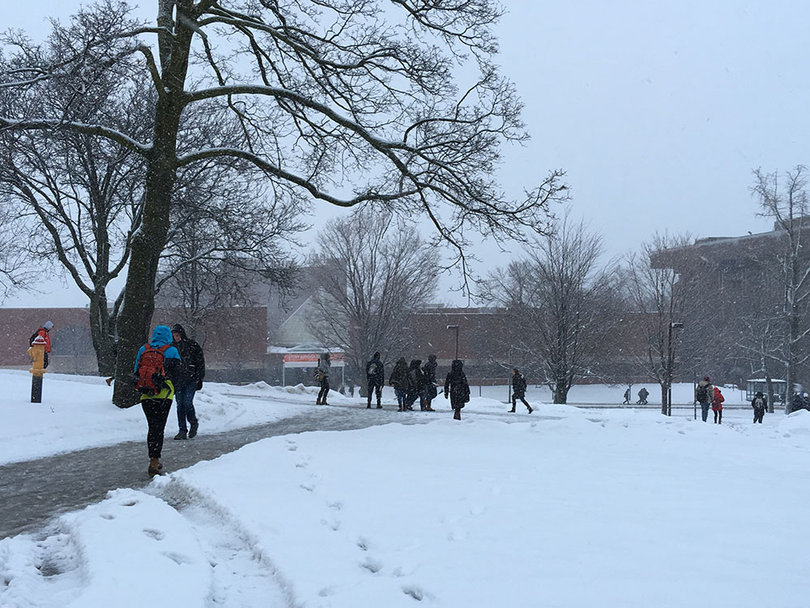Several students walk across the Quad, through a mixture of snow, water and ice.