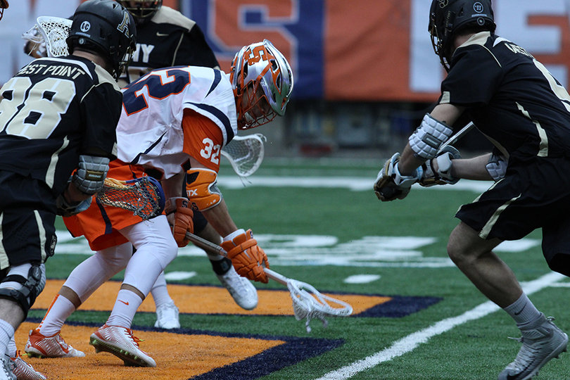 Syracuse midfielder Tom Grimm scoops up a groundball in a crowd of Army players. 