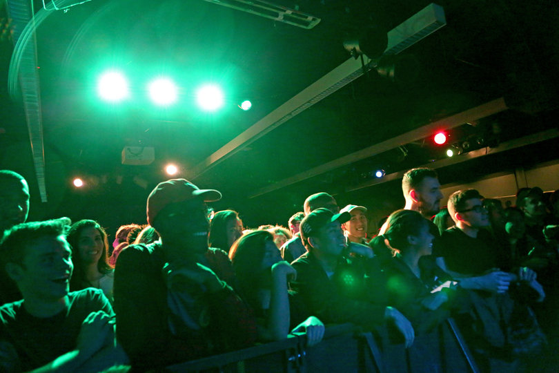 Members of the audience nod their heads along to the music as lights flash across the stage.