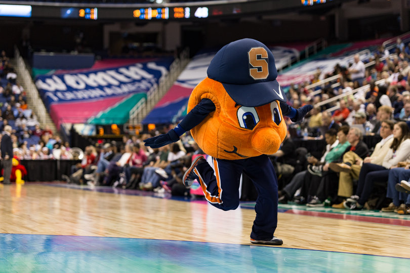Otto the Orange runs in the court with its hands extended to imitate an airplane during a break in the action.