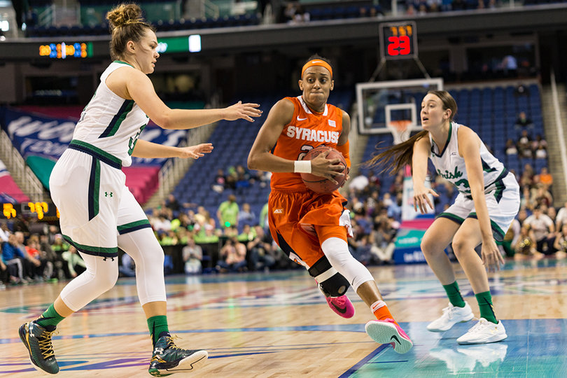 Brittney Sykes holds onto the ball as she charges through the paint between a pair of Notre Dame defenders.