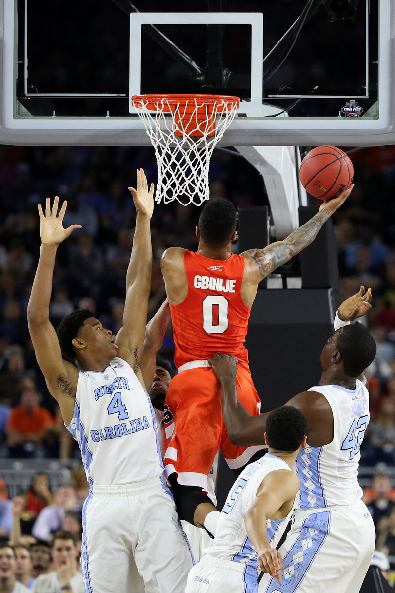 In his last game at Syracuse, Michael Gbinije fights through two North Carolina big men to attempt a layup. 