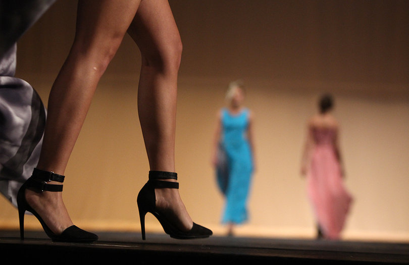 A model marches down the runway with her dress trailing behind.