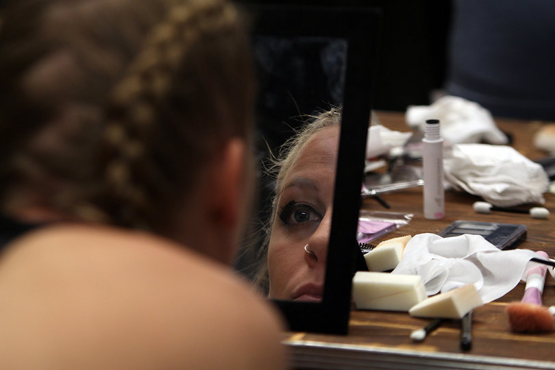 A model double checks her makeup and braided locks in a mirror.