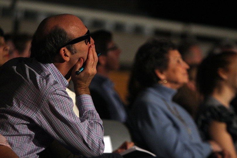 Audience members watch the show and mark down their thoughts on the outfits.