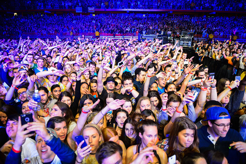 Crowd members throw their hands in the air and sway to Chance The Rapper's beats.